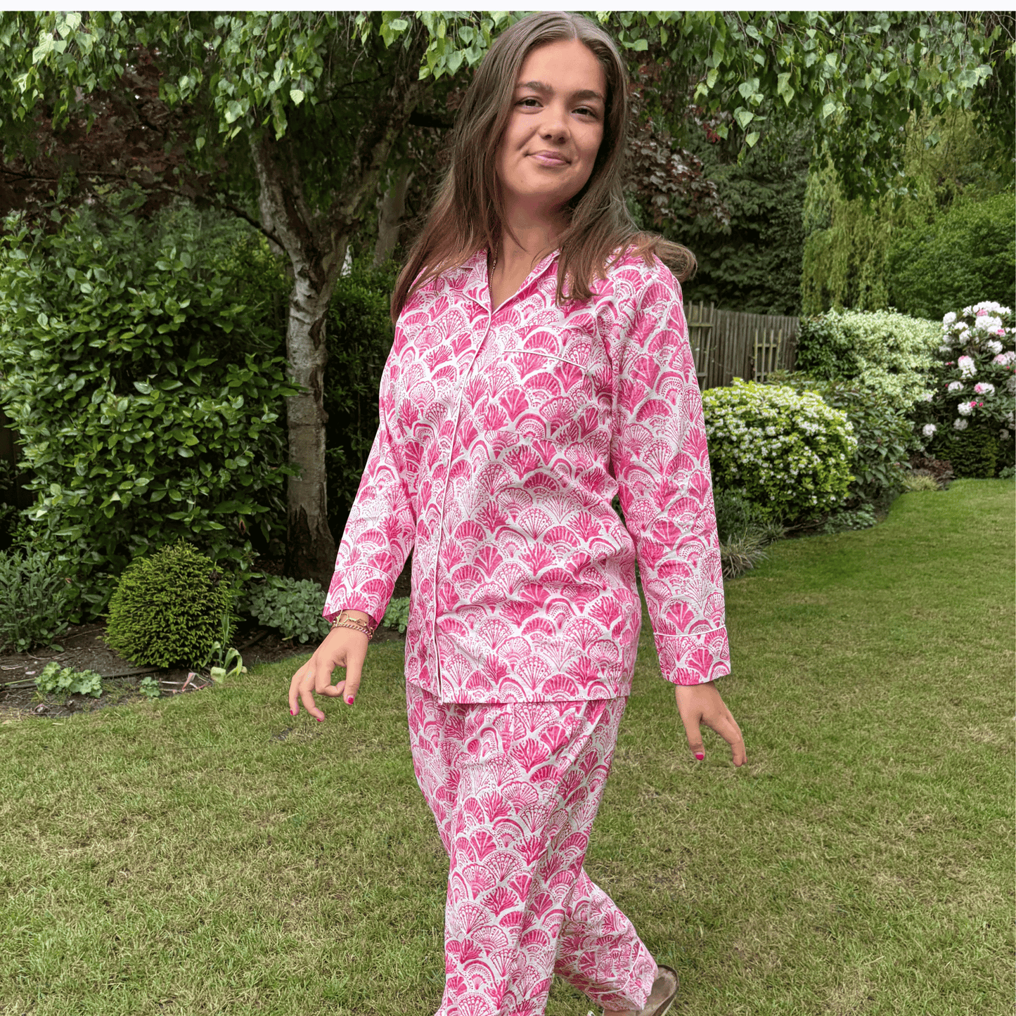 Bright pink shell print cotton pyjamas with long sleeves and elasticated drawstring waist on white background